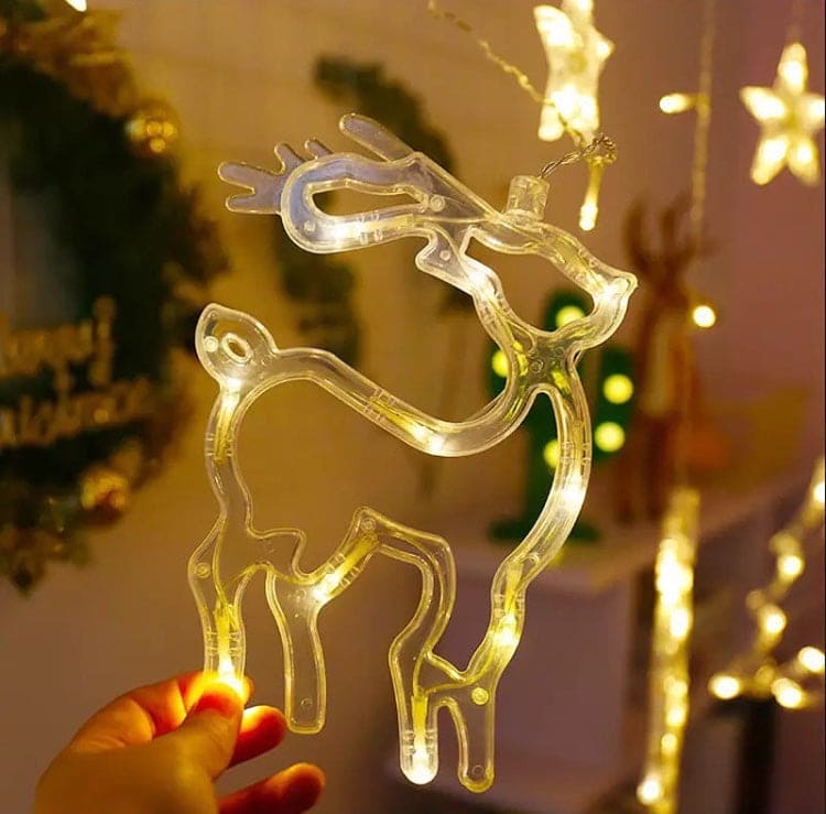 Clear reindeer Christmas star fairy lights decoration held in hand with warm glowing stars in background