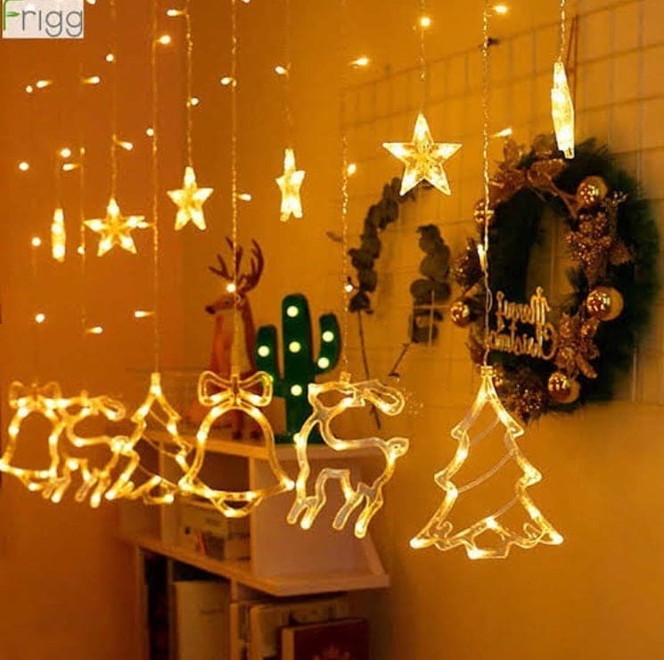 Warm white Christmas star fairy lights with hanging reindeer, bell, and tree decorations in cozy room