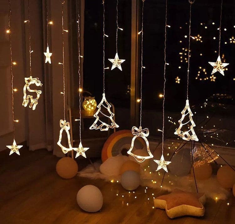 Warm white Christmas star fairy lights with hanging stars, bells, reindeer, and tree decorations in cozy room