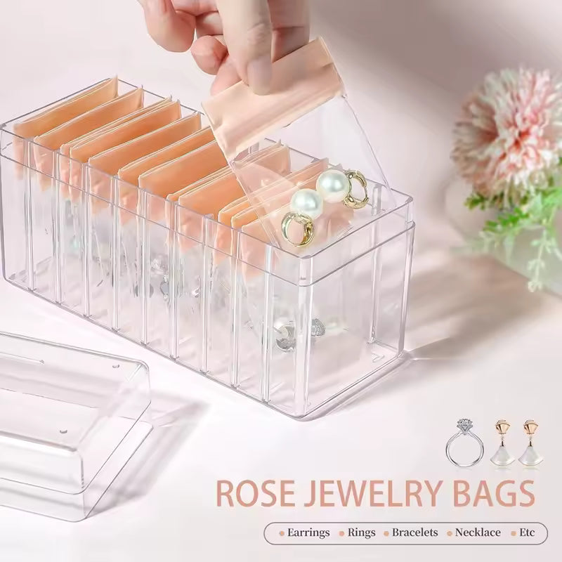 Clear jewelry organizer box with multiple rose gold jewelry bags holding earrings and rings