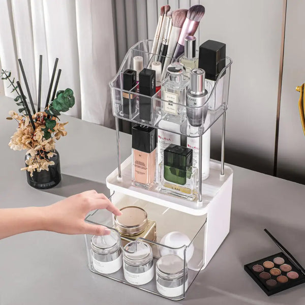 2-tier acrylic makeup organizer with clear compartments holding brushes lipsticks perfumes and a pull out drawer