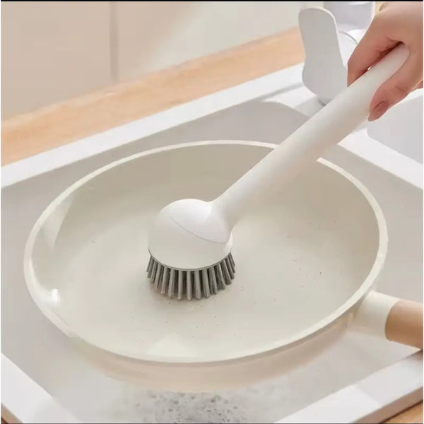 White long handle kitchen pot brush scrubbing a nonstick frying pan with gray bristles from Clarify pk