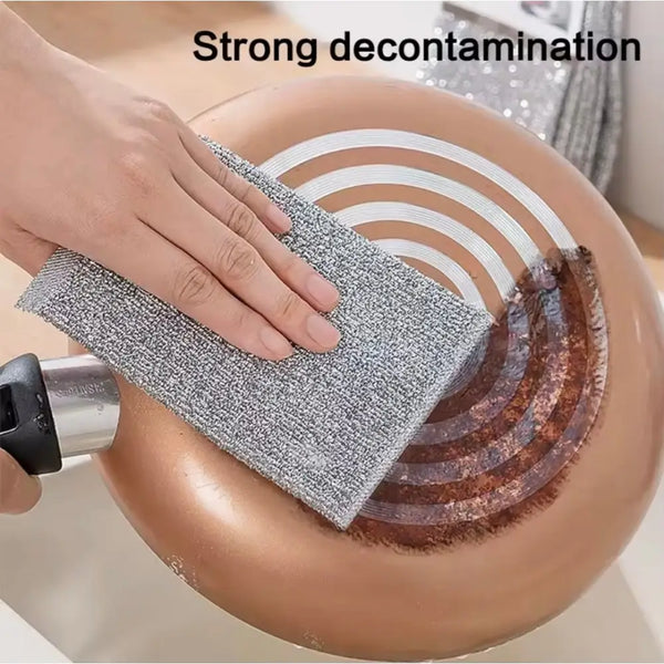 Hand scrubbing burnt copper pan base with gray double sided scrubber pads removing residue