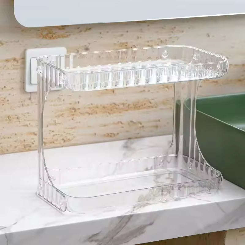 Clear double layer bathroom organizer made of plastic placed on marble countertop next to green sink