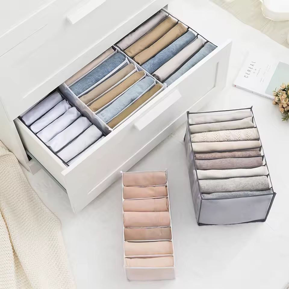 Closet organizer for clothes with multiple compartments neatly storing folded shirts and pants in a drawer and on the floor