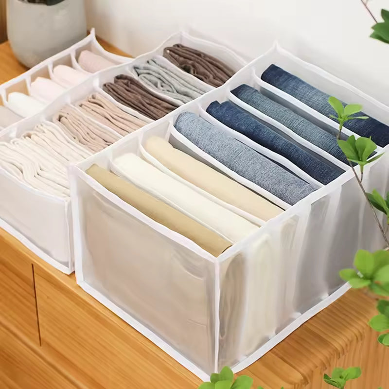 White fabric closet organizer for clothes with multiple compartments neatly storing folded shirts and pants