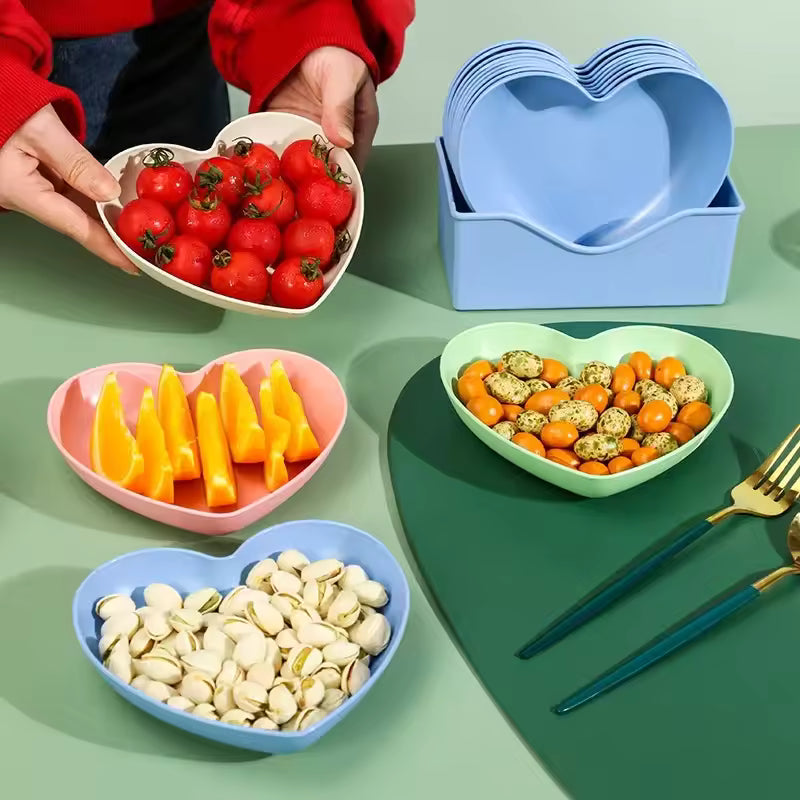 Colorful heart dish pack of plastic plates holding cherry tomatoes, mango slices, nuts, and snacks