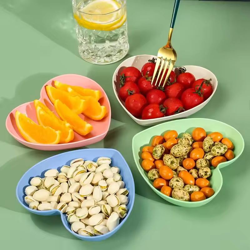 Colorful heart dish pack of plastic plates from Clarify.pk holding nuts, cherry tomatoes, orange slices, and snacks