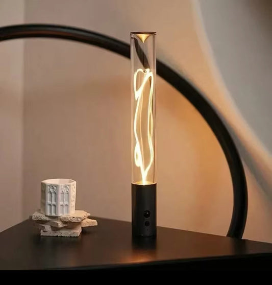 Modern cordless LED night light for room with sleek glass tube and warm glow on black base