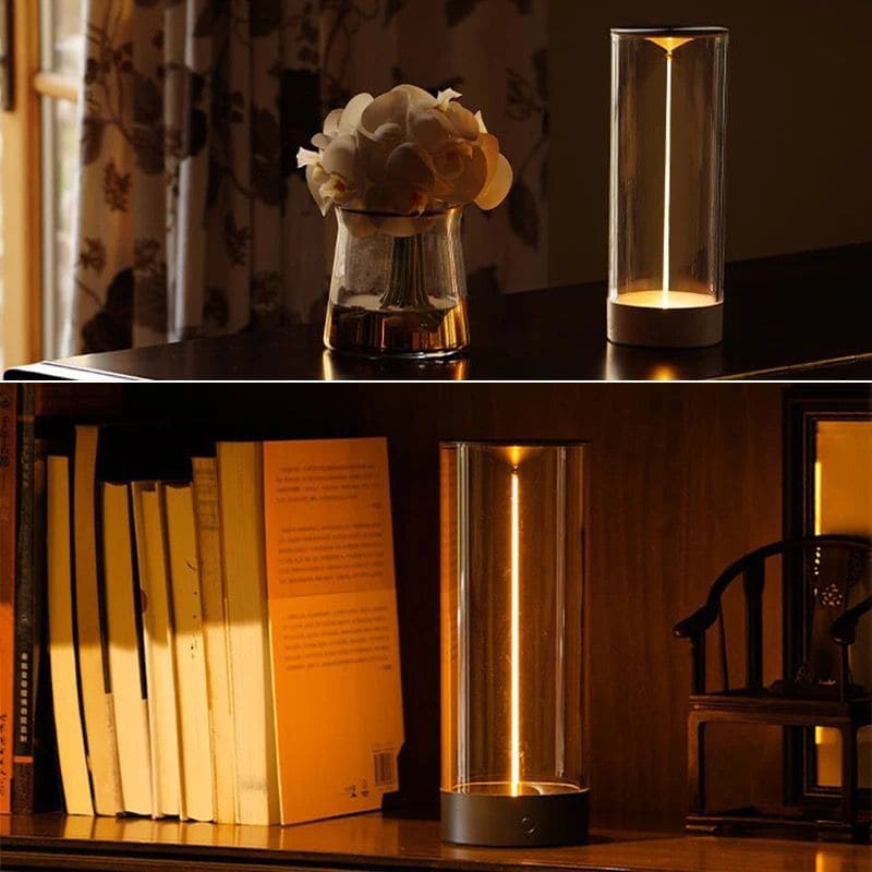 Cordless rechargeable table lamp with modern cylindrical glass design illuminating books and flowers