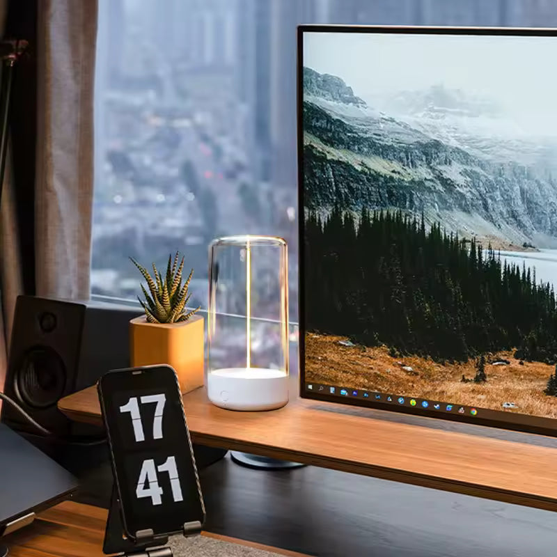 Cordless rechargeable table lamp on wooden desk beside computer monitor and smartphone stand