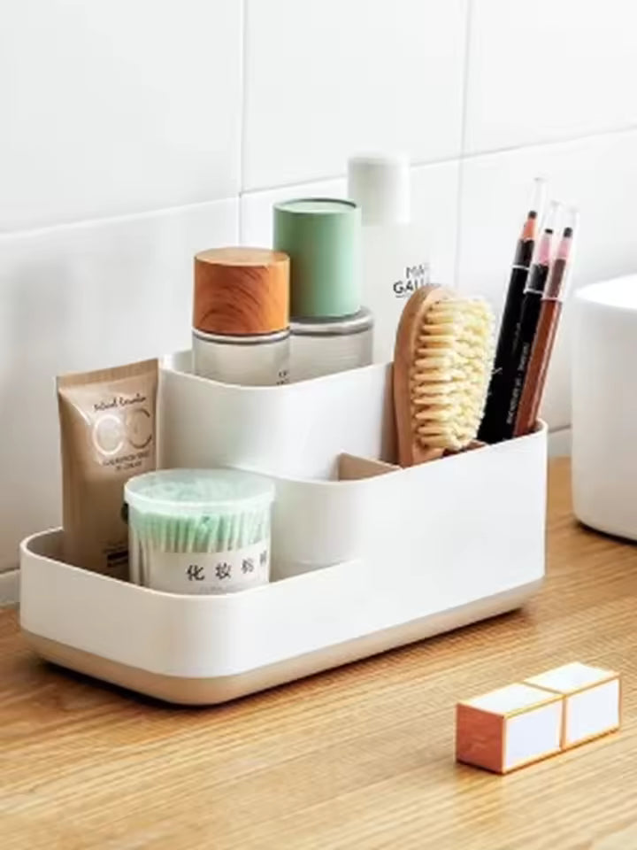 White cosmetic storage box with drawers holding skincare bottles, brushes, and makeup items on wooden countertop