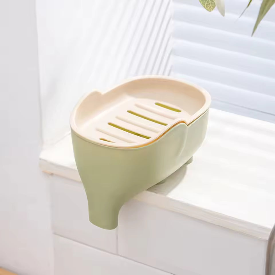 Creative animal soap holder for bathroom in green and beige mounted on white window ledge