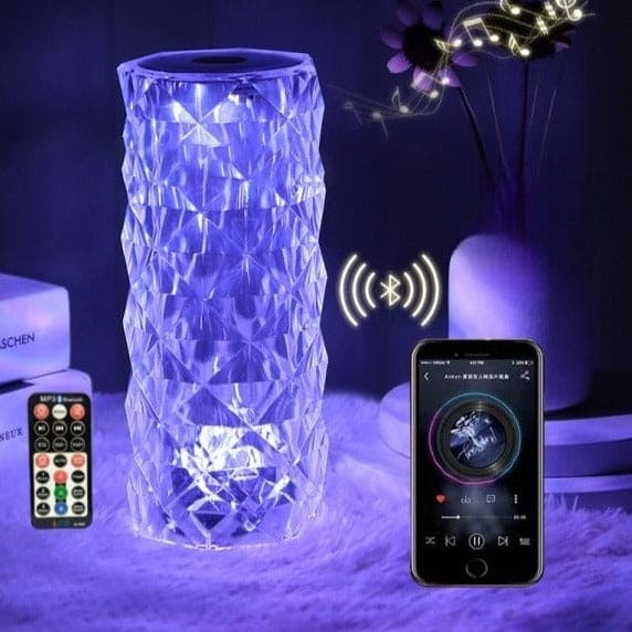 Crystal lamp with bluetooth speaker illuminated in blue light next to a smartphone and remote control