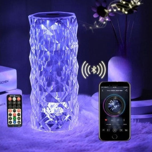 Crystal lamp with bluetooth speaker illuminated in blue light next to a smartphone and remote control