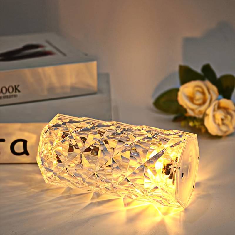 Warm glowing crystal rose Crystal lamp with faceted design placed on table near yellow roses