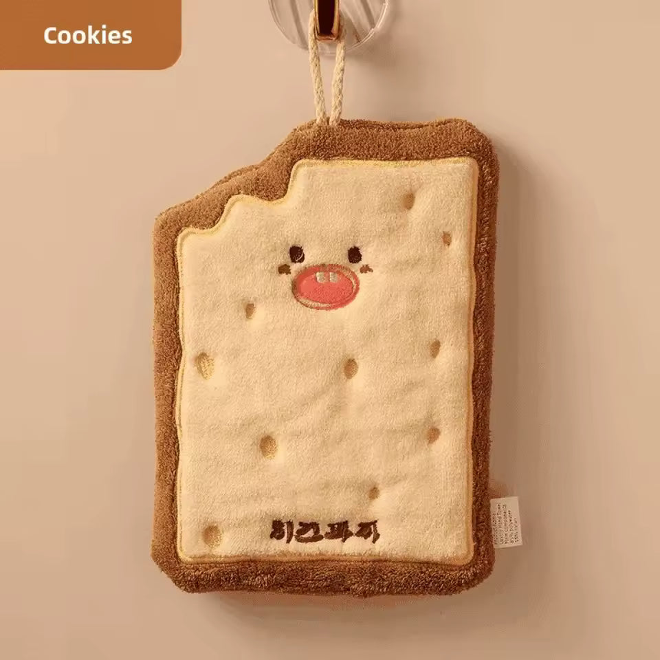 Cute coral velvet hand towels shaped like a cookie with a smiling face hanging on a hook