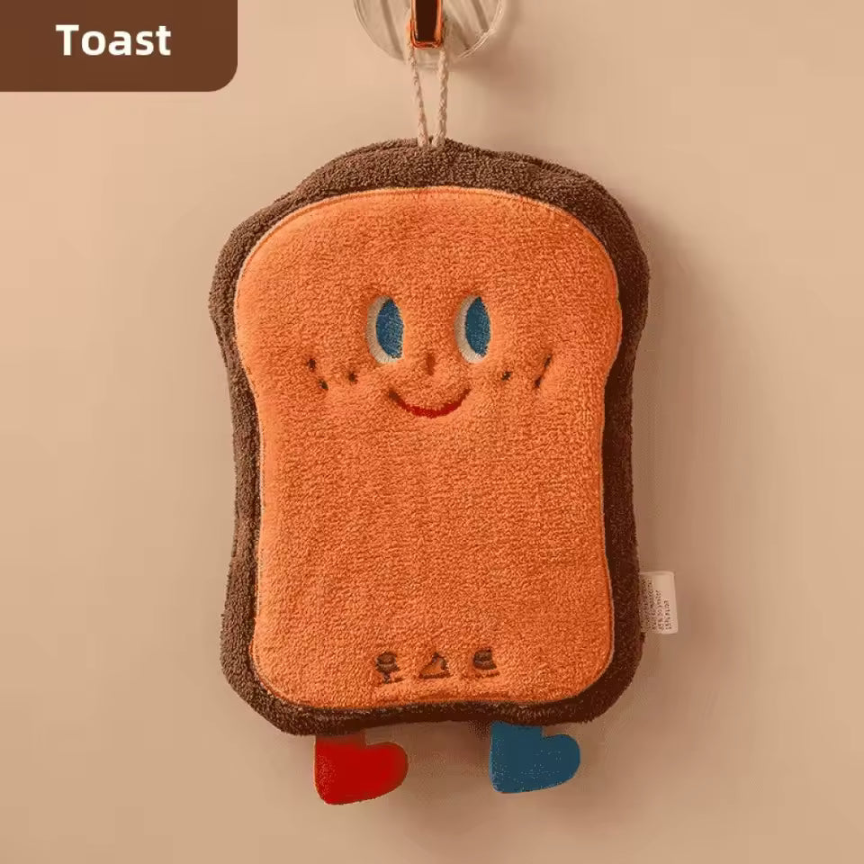 Cute coral velvet hand towels shaped like a smiling toast with blue and red feet hanging on a hook