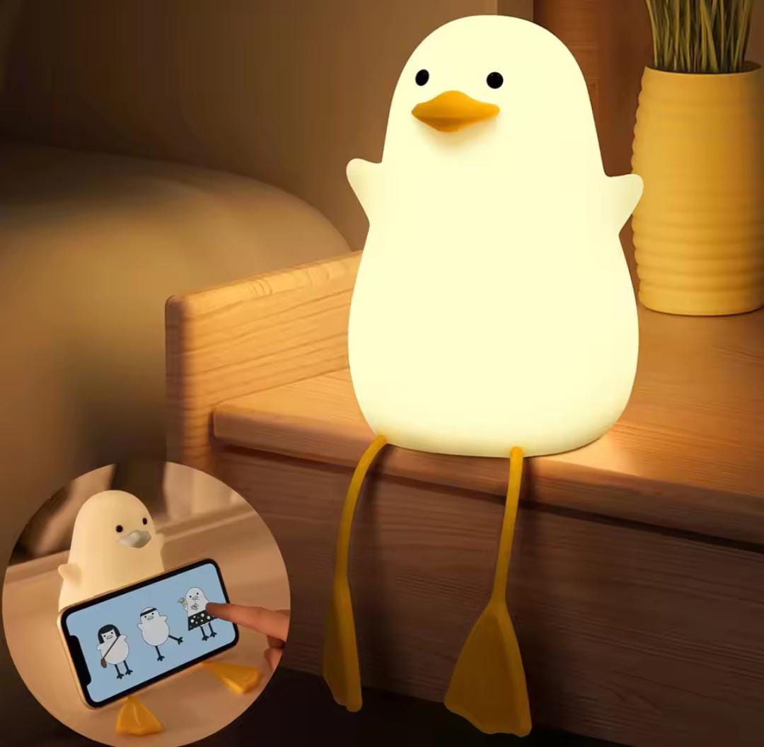 Cute duck night lamp glowing softly on wooden table with detachable legs holding a smartphone