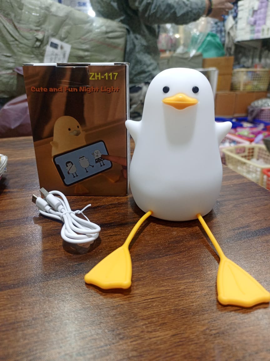 Cute duck night lamp with white body and yellow feet and beak by Clarify.pk on wooden table