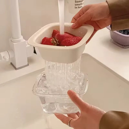 Hands holding a cute fruit drain basket washing strawberries with water draining into a clear container