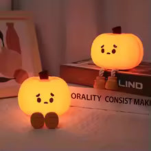 Cute silicone pumpkin night light glowing softly in a cozy room setting on a book
