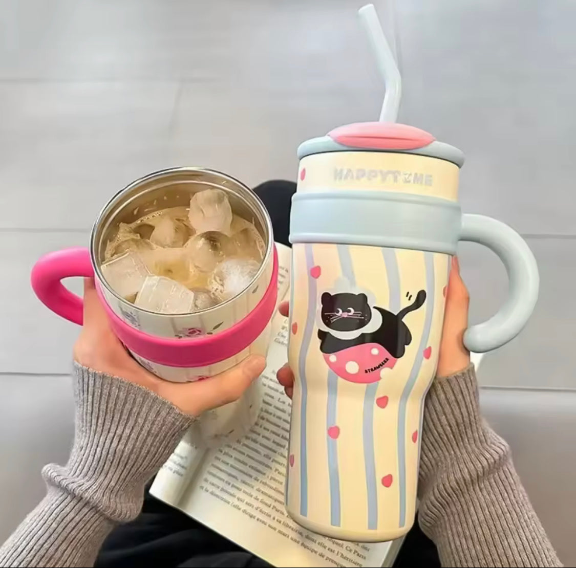 Cute stainless steel tumbler with straw featuring a cat design and pastel colors held by hands