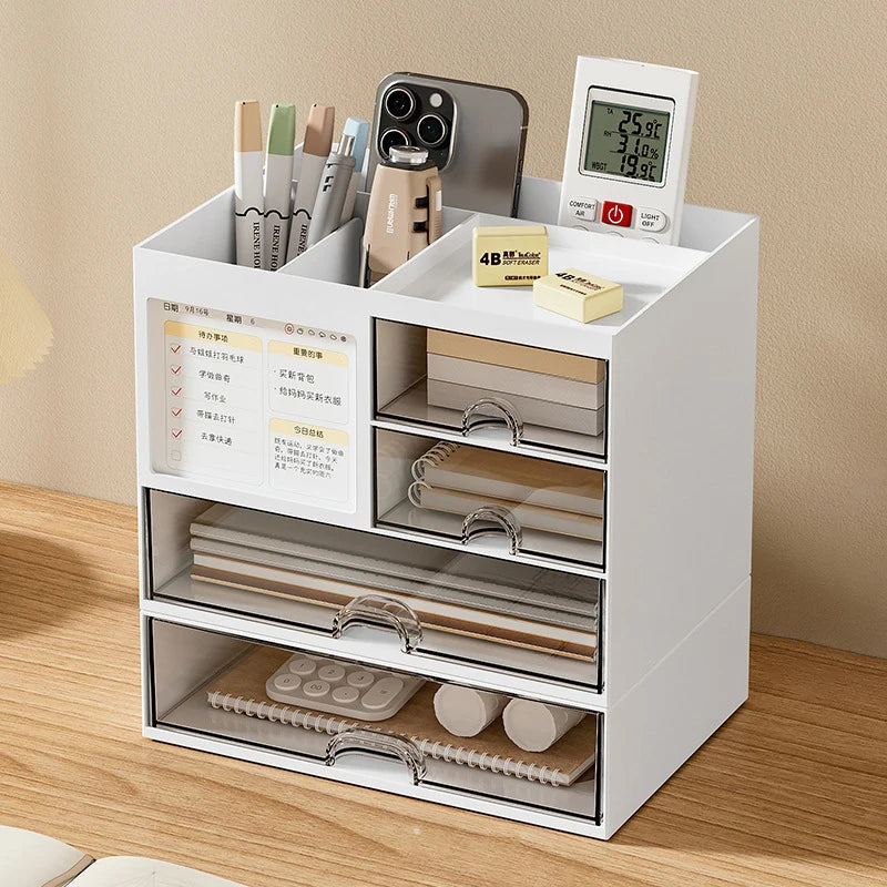 White desktop drawer storage box with multiple compartments holding pens, phone, sticky notes, and small office supplies