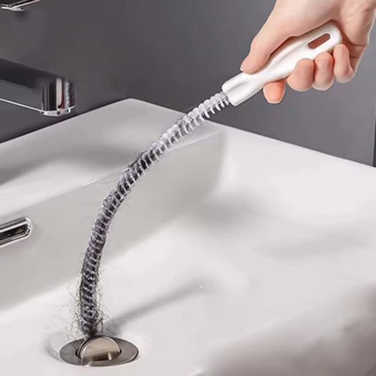 Hand using a white drain clog remover tool clearing hair from a bathroom sink drain