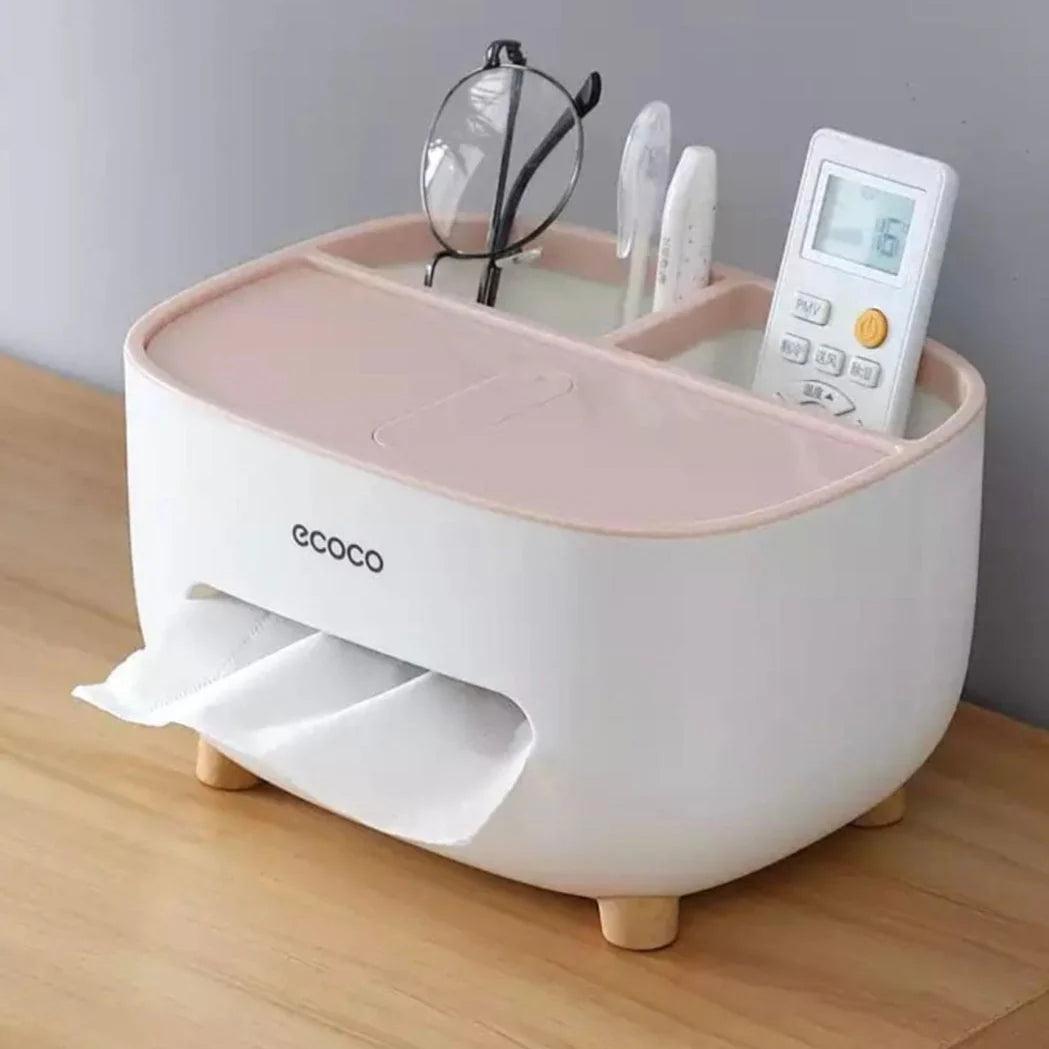 Ecoco tissue box holder in white and pink with storage compartments holding glasses and remote on wooden surface
