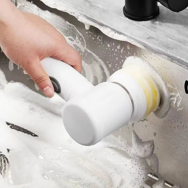 Hand using Clarify.pk electric cleaning brush to scrub soap and dirt from a kitchen sink surface