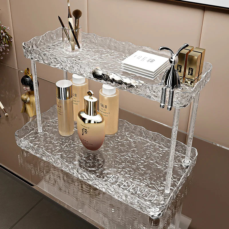 Transparent two-tier bathroom organizer shelves holding cosmetics and small items on a bathroom counter