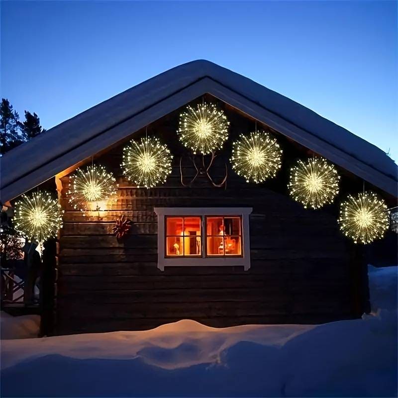 Firework string lights battery operated glowing in warm yellow hung on cabin roof edge at night
