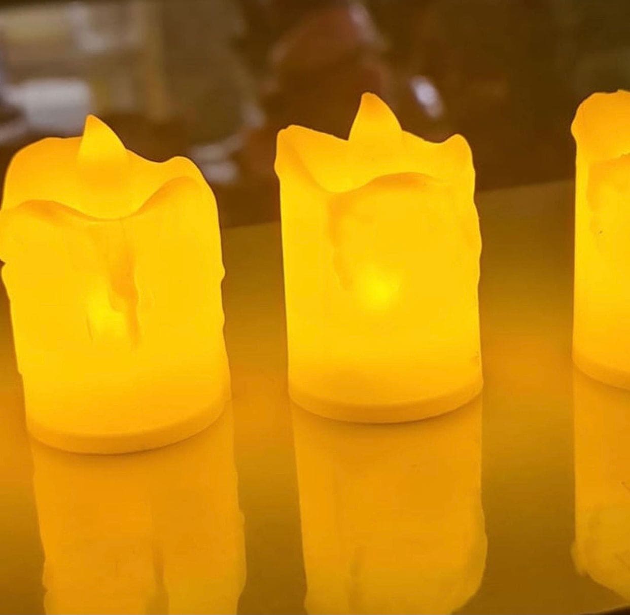 Warm glowing flameless LED tea lights set with realistic flickering flame effect on reflective surface