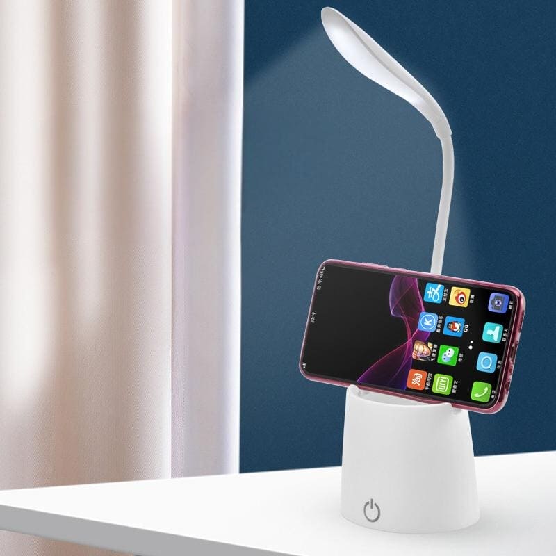 White flexible smart LED desk lamp with phone holder on a white table against blue and beige background