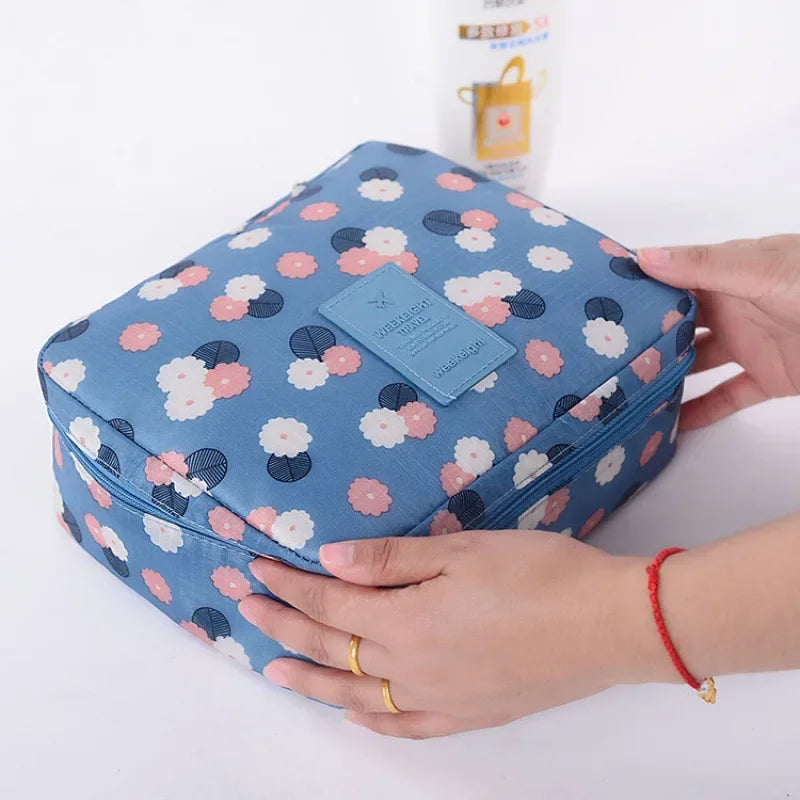 Blue floral makeup storage bag for women being held by hands with gold rings by Clarify.pk