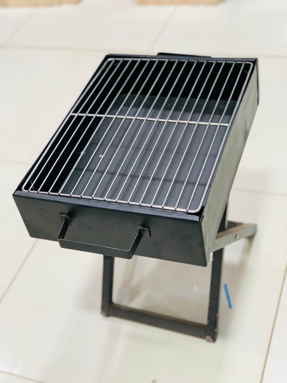 Compact black bbq grill for home use with metal grilling surface and foldable stand