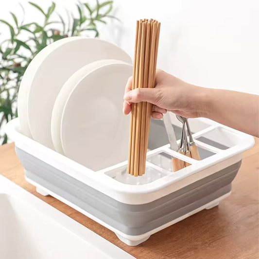 Foldable dish drainer rack holding plates chopsticks and utensils on wooden countertop