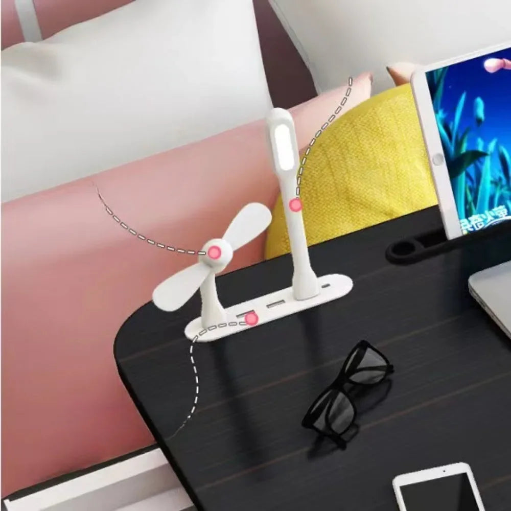 Foldable laptop desk with built-in USB fan and LED light next to tablet and glasses on bed