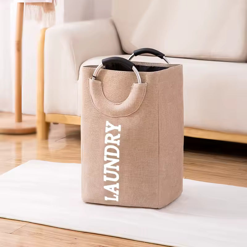 Clarify.pk foldable laundry hamper with handles in beige fabric with laundry text next to sofa