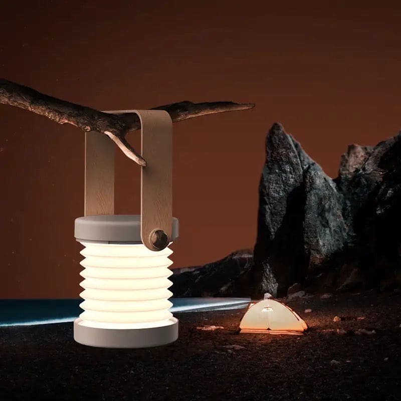 Clarify.pk foldable LED table lamp hanging from a branch illuminating a campsite at night