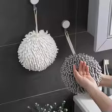 White and gray fuzzy ball microfiber hand towels hanging in bathroom with person drying hands