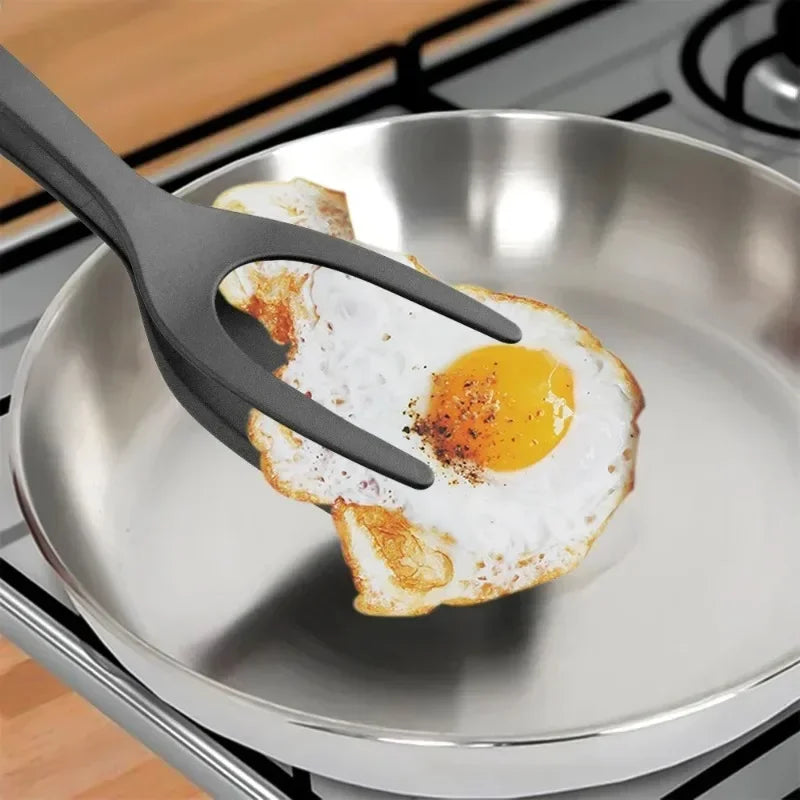 Clarify.pk 2 in 1 kitchen spatula lifting a fried egg from a stainless steel pan on stove