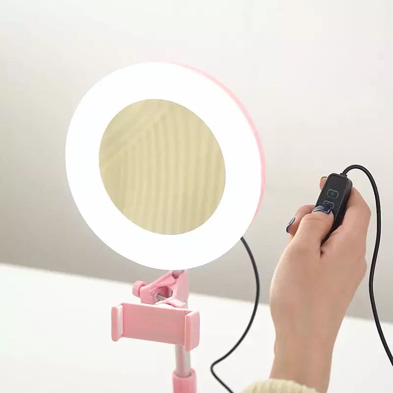 Foldable selfie stick with ring light in pink held by hand with remote control for selfies and video