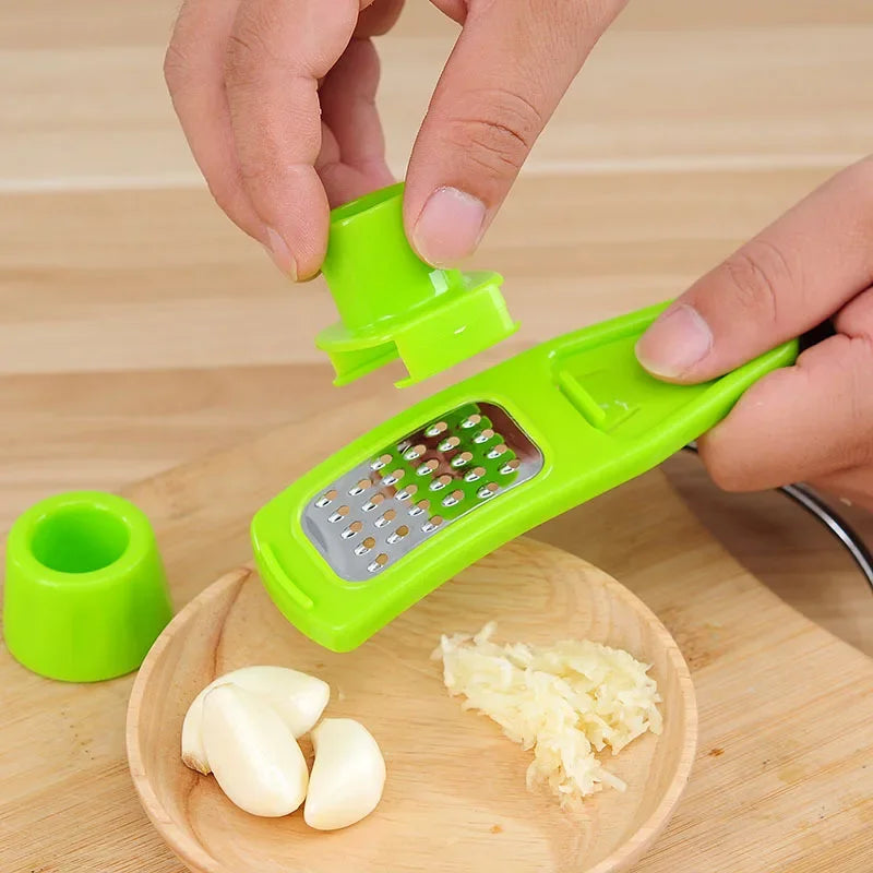 Green ginger garlic crusher tool with stainless steel grater and protective cap on wooden cutting board