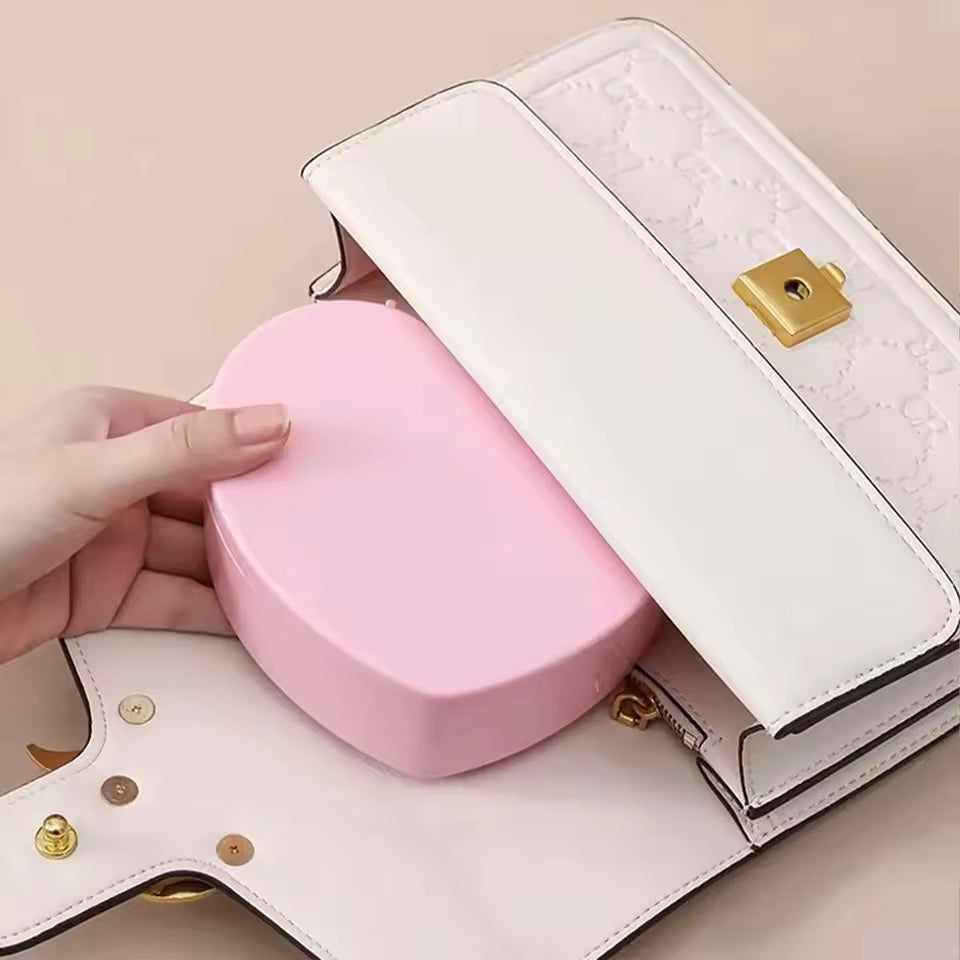 Pink heart shaped jewelry storage box being placed inside white handbag for organized storage