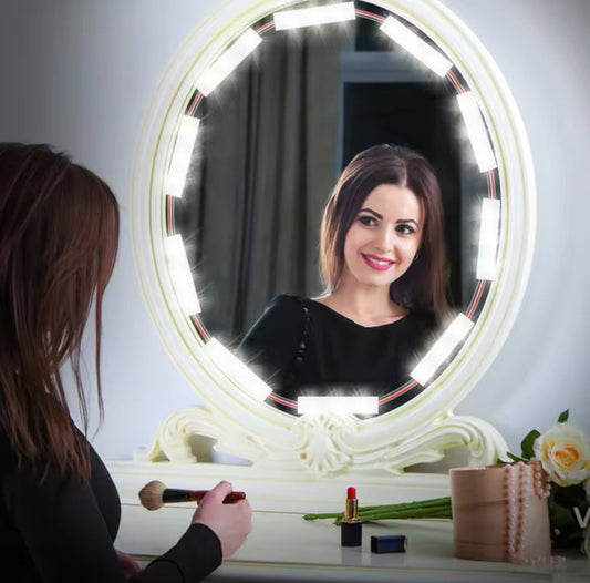 Woman using LED vanity mirror lights on an oval mirror while applying makeup at a white vanity