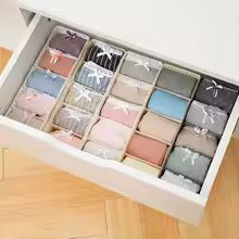 Organizer wardrobe drawer neatly filled with folded clothes in various pastel colors