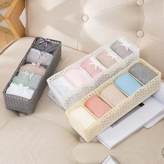 Plastic organizer wardrobe trays holding neatly rolled colorful socks on a beige couch