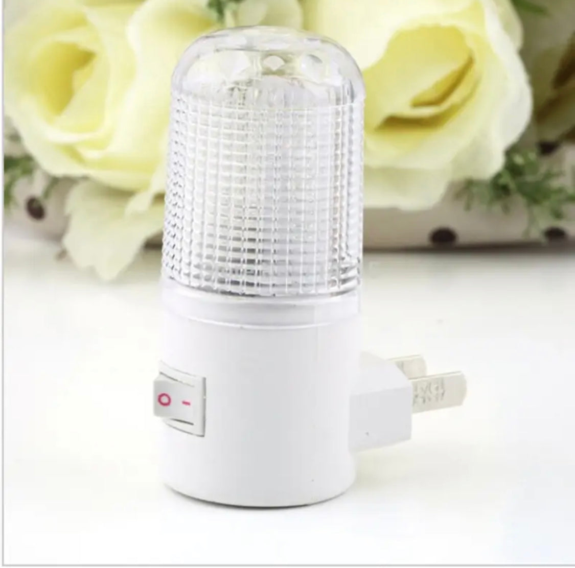 White wall mounting night lamp with textured clear cover and power switch plugged into wall outlet